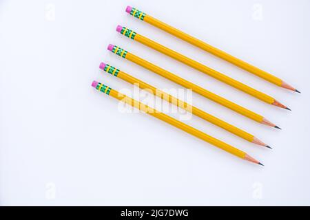 Der negative Raum wird mit fünf spitzen Bleistiften genutzt, die schräg auf einem weißen Blatt Papier ausgerichtet sind. Stockfoto