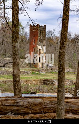 Im Glendale Shoals Nature Preserve, einem ehemaligen Baumwollmischungswerk in Spartanburg, South Carolina, ist noch ein gotischer, roter Ziegelturm erhalten. Stockfoto