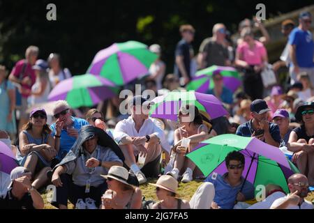 Am 12. Tag der Wimbledon Championships 2022 im All England Lawn Tennis and Croquet Club, Wimbledon, schützen sich die Zuschauer vor der Sonne. Bilddatum: Freitag, 8. Juli 2022. Stockfoto