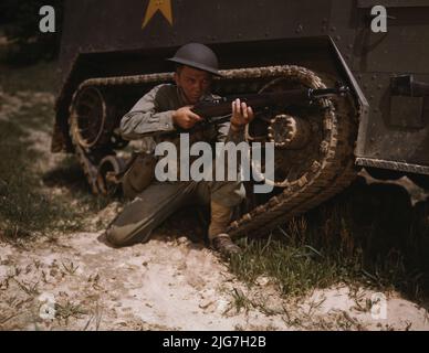 Ein junger Soldat der gepanzerten Streitkräfte hält und visiert sein Garand-Gewehr wie ein alter Timer, Fort Knox, Ky. Er mag das Stück wegen seiner feinen Brenneigenschaften und seines robusten, zuverlässigen Mechanismus. Infanterist mit Halftrack. Stockfoto