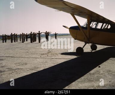 Zivilluftwaffenstützpunkt, Bar Harbor, Maine. Das Foto zeigt Männer, die auf dem Flugfeld neben dem Stinson HW-75 oder 105 Voyager trainieren. Das Design wurde später für den Krieg auf die L-5-Wache umgestellt. Stockfoto