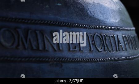 Lateinische Inschrift auf einer Metallglocke auf Schloss Hohenwerfen, Österreich, zeigt historische Handwerkskunst und mittelalterliches Festungserbe. Stockfoto