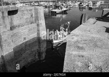 Fischerboote, die den Hafen in Porthleven, Cornwall, betreten und verlassen Stockfoto