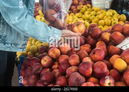 Kauf von frischen Bio-Produkten auf dem Bauernmarkt. Eine Frau wählt auf einem Lebensmittelmarkt frische Kräuter, Gemüse und Früchte. Stockfoto