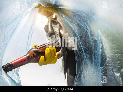 Nahaufnahme einer Frau, die Müll in eine Plastiktüte wirft. Blick von der Innenseite der Tasche. Das Konzept der Sorge um die Umwelt und des Recyclings Stockfoto