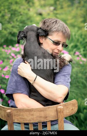 Porträt einer Frau, die einen Hund umarmt Stockfoto