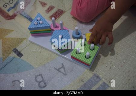 Kinderhand, spielt mit montessory Spielzeug. Geometrie Puzzle. Bildung für Kinder, die natürliche Interessen und Aktivitäten zu entwickeln sucht. Stockfoto