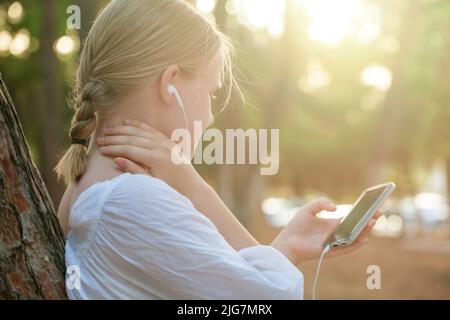 Junge Teenager-Mädchen hören Musik. Studentin Mädchen draußen im Park Musik auf Kopfhörer hören Stockfoto