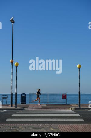 Straßenüberquerung zur Promenade und zum Southsea Beach in Portsmouth mit einem Jogger, der vorbeiläuft. Stockfoto