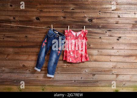 Kindermode-Set aus Mädchenbekleidung, Bluse und Jeans; Foto auf Holzhintergrund. Stockfoto