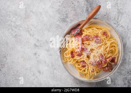 Carbonara Pasta. Spaghetti mit Pancetta, Ei, Parmesankäse und Sahnesauce auf altem grauen Betontisch-Hintergrund. Traditionelle italienische Küche und Stockfoto