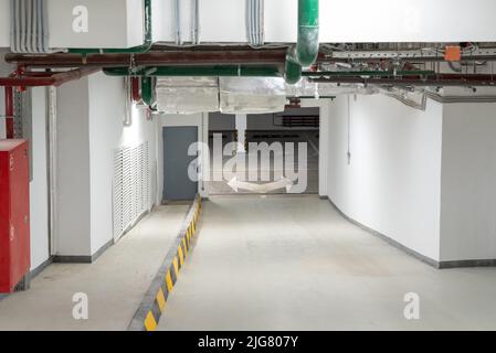 Eingang zur Tiefgarage eines Wohngebäudes und Bewegungsrichtung in der Garage. Neues Haus. Stockfoto