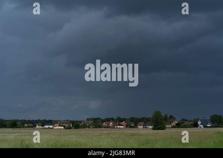 Dunkle Regenwolken kurz vor einem Sturm über einem kleinen Dorf in der Nähe der Stadt Luckenwalde in Deutschland Stockfoto