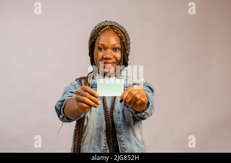 Eine schwarze Dame, die eine Visitenkarte in den Händen auf einem Studiohintergrund hält Stockfoto