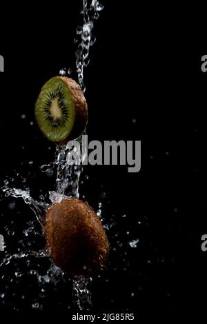 Eine spritzte, geschnittene Kiwi-Frucht, isoliert auf schwarzem Hintergrund Stockfoto