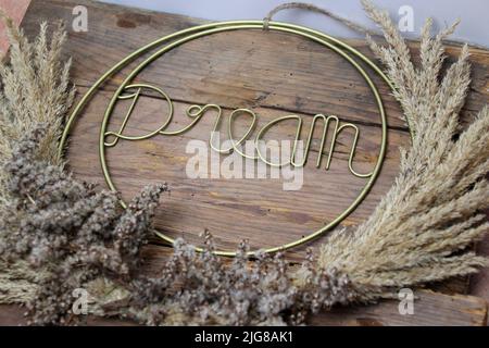 Schriftzug, Traum, auf Holzhintergrund, eingerahmt von Gräsern, Dekoration Stockfoto