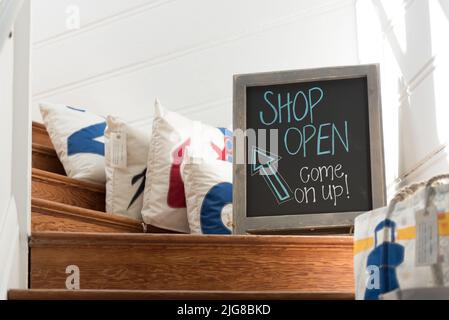 Eine Nahaufnahme eines Schreibtisches mit einer Nachricht eines offenen Ladens auf einer Treppe Stockfoto