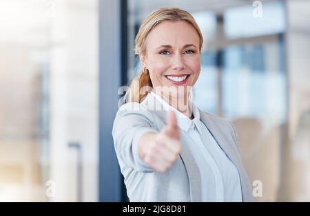 Tippen Sie zweimal, wenn Sie lieben, was wir tun. Porträt einer reifen Geschäftsfrau mit Daumen nach oben in einem modernen Büro. Stockfoto