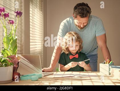 Bärtiger Vater schreibt Schulaufgaben mit seinem Sohn im Klassenzimmer, moderne Bildung Stockfoto