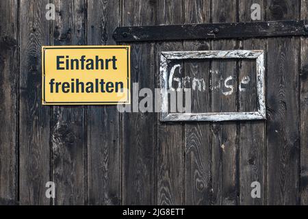 Zwei Schilder, halten Sie die Auffahrt frei und handgeschriebenes Schild „Gemüse“. Stockfoto