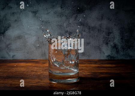 Eiswürfel fallen in ein Glas Stockfoto