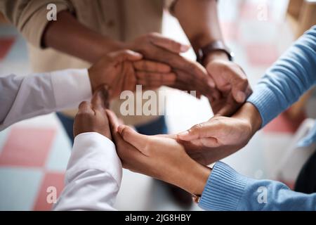 Einheit ist notwendig, um eure Vision zu erreichen. Aufnahme einer Gruppe von Geschäftsleuten, die sich in einem modernen Büro solidarisch zusammenschließen. Stockfoto