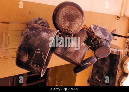 Eine Nahaufnahme von alten Töpfen und Pfannen, die an einer Küchenwand hängen Stockfoto