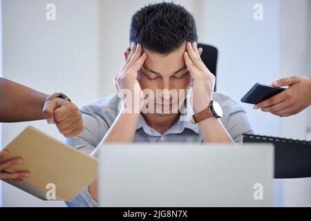 Es gibt zu viel zu tun. Aufnahme eines reifen Geschäftsmannes, der in einem stressigen Arbeitsumfeld überfordert aussieht. Stockfoto
