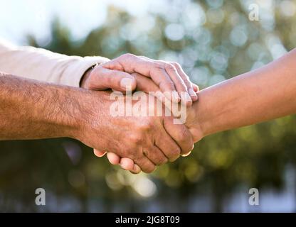 Am Ende des Tages wird alles in Ordnung sein. Aufnahme von zwei unverkennbaren Männern, die die Hände im Freien halten. Stockfoto