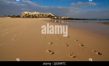 Spanien, Kanarische Inseln, Fuerteventura, Corralejo, Weitwinkelaufnahme, Sandstrand, Fußabdrücke, Hotelkomplex, himmelblau mit Wolken Stockfoto