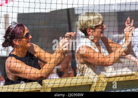 Sandbanks, Poole, Dorset, Großbritannien . 8.. Juli 2022. Die Sandpolo British Beach Polo Championships beginnen an einem heißen, sonnigen Tag am Strand von Sandbanks in Poole. Anlässlich des 15.-jährigen Bestehens die zweitägige Veranstaltung, die als größte Strandpoloveranstaltung der Welt stattfindet, findet am Freitag und Samstag statt, während Besucher sich am Strand die Action ansehen. Zwei Zuschauerinnen, die das Geschehen auf ihren Smartphones festhalten. Quelle: Carolyn Jenkins/Alamy Live News Stockfoto