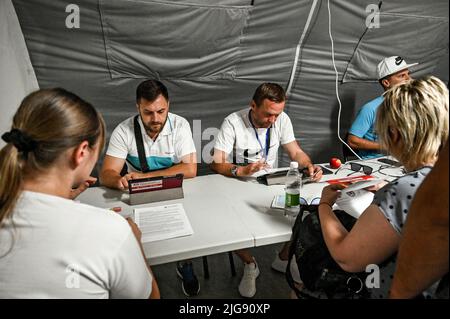 ZAPORIZHZHIA, UKRAINE - 8. JULI 2022 - Freiwillige helfen Menschen an der modernisierten größten Drehscheibe für Binnenvertriebene, die vor russischen Invasoren geflohen sind, Stockfoto