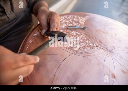 Handwerker arbeitet mit Dekorationsmuster auf Metallplatte Stockfoto