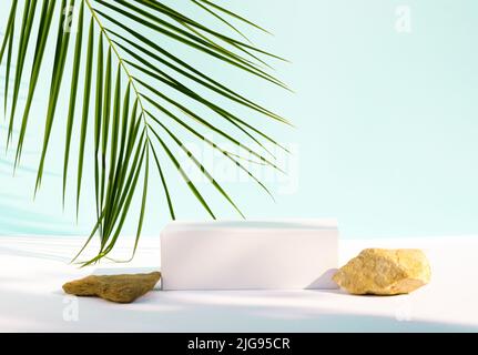 Hintergrund für kosmetische Produkte. Moderne Produktanzeige auf blauem Hintergrund mit Steinpodium und tropischem Palmenblatt. Geeignet für Produktanzeige und Stockfoto