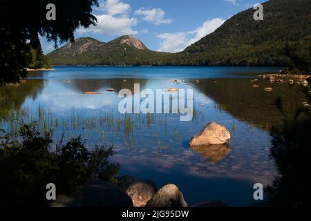 Jordan Pond im Acadia National Park, Bar Harbor, Maine, USA. Wunderschöne Landschaft mit Felsen, silhouettierten Bäumen, Reflexionen, Wolken und tiefen Schatten. Stockfoto