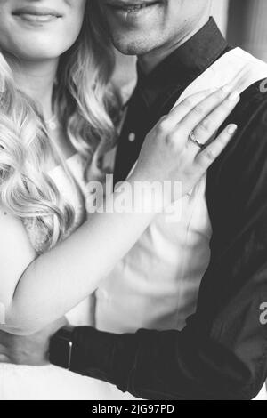 Eine vertikale Graustufenaufnahme der Braut und des Bräutigams, die sich am Hochzeitstag in Kopenhagen, Dänemark, umarmen Stockfoto