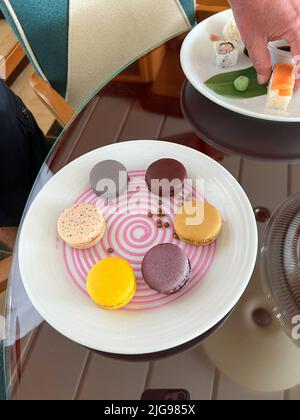 Ein Desserttablett mit Makronen-Keksen, mit Schokolade überzogenen Erdbeeren, Trüffeln und Kuchen auf einem dekorierten Teller. Stockfoto