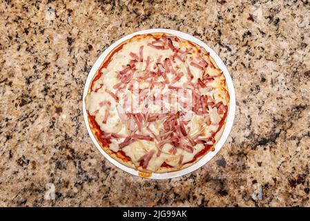 Kleine Pizza mit viel Speck und Zwiebelstreifen, losem Mozzarella-Käse und Tomatensauce auf einer gebackenen Pizza Stockfoto