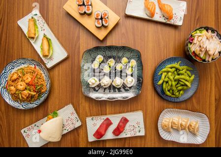 Set von asiatischen Gerichten mit Sushi, Avocado Maki, Garnelennudeln, Edamame-Bohnen, Gyozas, norwegischer Lachs und bao-Brot Stockfoto