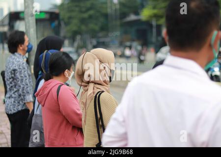 Ein Blick auf Menschen in Masken, die darauf warten, die Straße zu überqueren Stockfoto