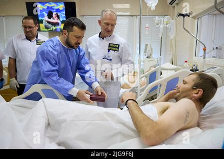 Dnipro, Ukraine. 08.. Juli 2022. Der ukrainische Präsident Wolodymyr Zelenskyy wird von Dr. Serhiy Ryzhenko begleitet, als er sich während eines Besuchs im Mechnikov-Krankenhaus am 8. Juli 2022 in Dnipro, Dnipropetrowsk, Ukraine, mit verletzten Kriegern trifft. Kredit: Ukrainische Präsidentschaft/Ukrainische Presidential Press Office/Alamy Live Nachrichten Stockfoto