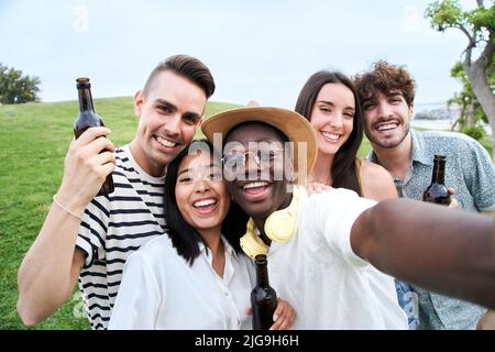 Eine Gruppe von fünf fröhlichen jungen Freunden, die Selfie-Portraits machen. Glückliche Menschen, die lächelnd auf die Kamera blicken. Konzept der Gemeinschaft, Jugend Lebensstil und Stockfoto