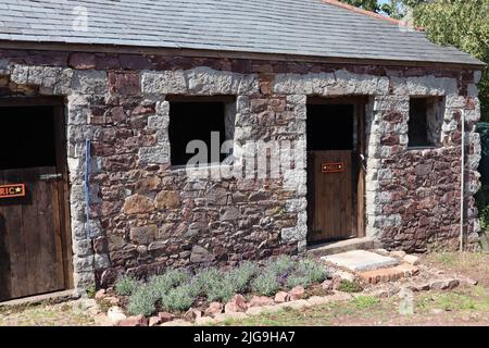 Ein sehr solider und moderner Ziegelstall. Die britische Exzentrizität zeigt sich durch die Namen von Eric und Nell für die beiden Reiter Stockfoto