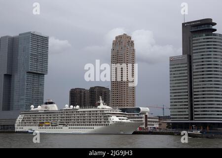 Ein Kreuzfahrtdampfer dockte an der Rotterdamer Uferpromenade am Fluss Nieuwe Maas an, mit Gebäuden wie dem De Rotterdam-Gebäude, Rotterdam, Niederlande Stockfoto