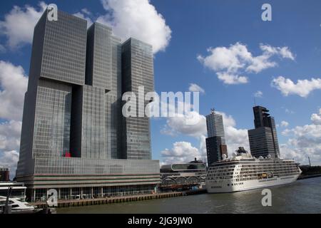 Ein Kreuzfahrtdampfer dockte an der Rotterdamer Uferpromenade am Fluss Nieuwe Maas an, mit Gebäuden wie dem De Rotterdam-Gebäude, Rotterdam, Niederlande Stockfoto