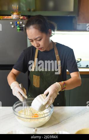 Junge Vietnamesin, die Teig für einen Kuchen mischt Stockfoto