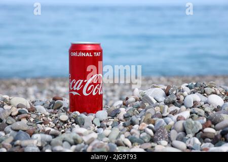 ANTALYA, TÜRKEI - 18. MAI 2021: Original Coca Cola rote Blechdose liegt auf kleinen runden Kieselsteinen nahe der Küste. Coca-Cola auf türkischen Strandsteinen Stockfoto