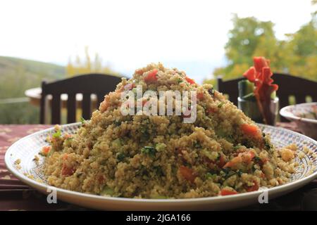 Tabbouleh mit Koriander-Tomaten minzen Gurkenkräuter auf einem Tisch in den Bergen Stockfoto