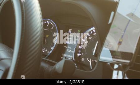 Beleuchtete Tachometer-Instrumententafel und Lenkrad eines modernen Autos in einem Sonneneinstrahlung. Stockfoto