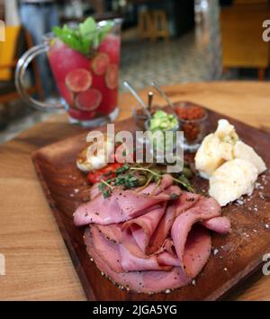 Speck, Käse, Tomaten, Gebäck und Krug Mojito auf dem Restauranttisch. Stockfoto